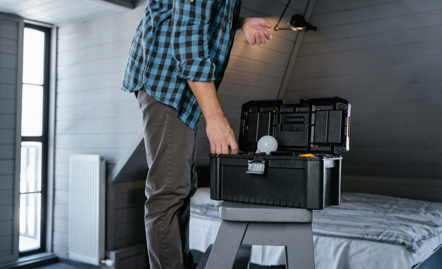 man on a stepladder reaching into an open black toolbox